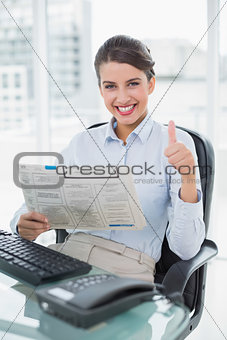 Cheering classy brown haired businesswoman reading a newspaper