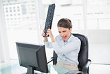 Furious classy brown haired businesswoman throwing her keyboard on her computer