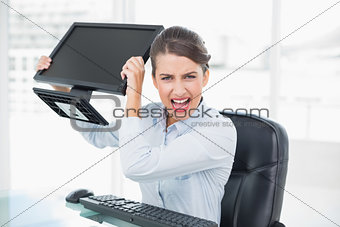 Annoyed classy brown haired businesswoman throwing her computer screen
