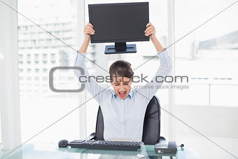 Angry classy brown haired businesswoman throwing her computer screen