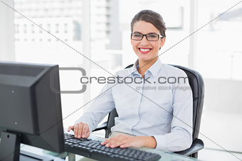 Cheerful classy brown haired businesswoman typing on a computer