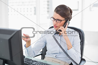 Frowning classy brown haired businesswoman answering the telephone
