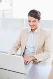 Smiling smart brown haired businesswoman using a laptop