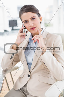 Thoughtful smart brown haired businesswoman making a phone call