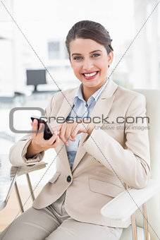 Pleased smart brown haired businesswoman using a mobile phone