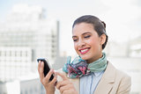 Amused smart brown haired businesswoman using a mobile phone