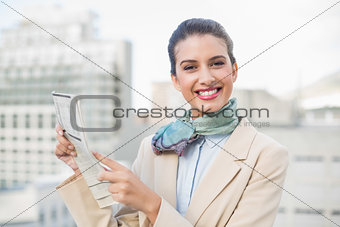 Cute smart brown haired businesswoman holding a newspaper