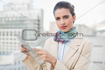 Serious smart brown haired businesswoman holding a newspaper