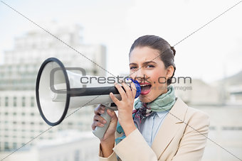 Irritated smart brown haired businesswoman using a megaphone