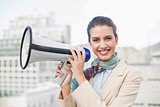 Happy smart brown haired businesswoman holding a megaphone