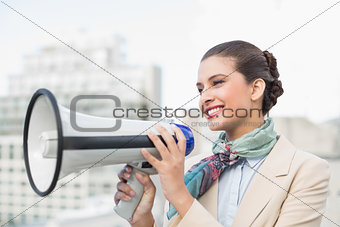 Pleased smart brown haired businesswoman holding a megaphone
