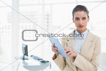 Serious smart brown haired businesswoman holding a tablet pc