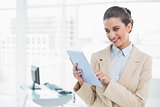 Pleased smart brown haired businesswoman using a tablet pc