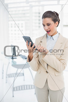 Amazed smart brown haired businesswoman using a calculator