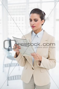 Attentive smart brown haired businesswoman reading a newspaper