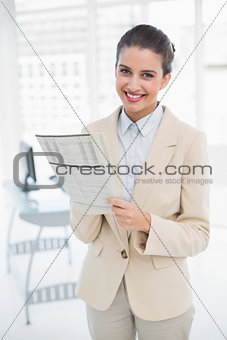 Content smart brown haired businesswoman reading a newspaper