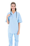 Smiling brown haired nurse in blue scrubs looking at camera