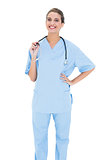 Happy brown haired nurse in blue scrubs looking at camera
