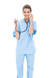 Content brown haired nurse in blue scrubs holding her stethoscope