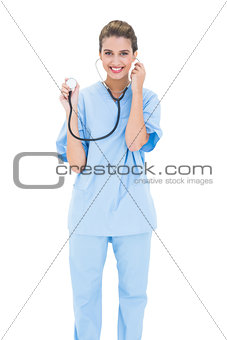 Content brown haired nurse in blue scrubs holding her stethoscope