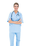 Smiling brown haired nurse in blue scrubs posing with arms crossed