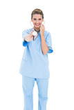 Amused brown haired nurse in blue scrubs playing with her stethoscope