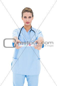 Stern brown haired nurse in blue scrubs showing a medication box