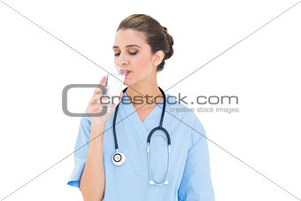 Peaceful brown haired nurse in blue scrubs drinking milk