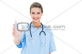 Content brown haired nurse in blue scrubs holding a glass of water