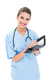 Content brown haired nurse in blue scrubs filling an agenda