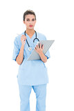 Serious brown haired nurse in blue scrubs checking a report