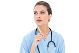 Thoughtful brown haired nurse in blue scrubs holding a pen