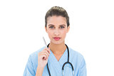Serious brown haired nurse in blue scrubs holding a pen