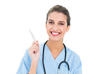 Pleased brown haired nurse in blue scrubs holding a pen