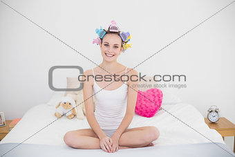 Smiling natural brown haired woman in hair curlers practicing yoga
