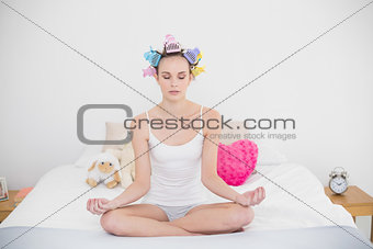 Calm natural brown haired woman in hair curlers practicing yoga