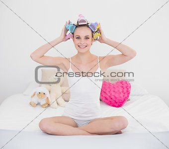 Pretty natural brown haired woman fixing her hair curlers