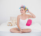 Content natural brown haired woman fixing her hair curlers