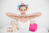 Serious natural brown haired woman in hair curlers posing looking at camera