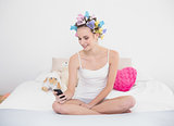 Pleased natural brown haired woman in hair curlers using her mobile phone
