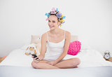 Content natural brown haired woman in hair curlers using her mobile phone