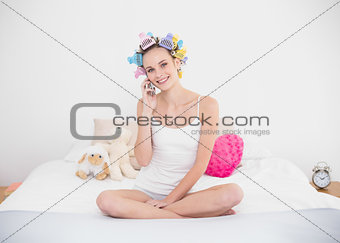 Delighted natural brown haired woman in hair curlers making a phone call