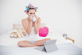 Peaceful natural brown haired woman in hair curlers drinking coffee
