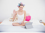 Charming natural brown haired woman in hair curlers chatting online with a tablet pc