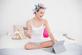 Pretty natural brown haired woman in hair curlers shopping online with her tablet pc