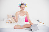 Joyful natural brown haired woman in hair curlers shopping online with her tablet pc