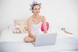 Attractive natural brown haired woman in hair curlers using a laptop