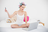 Crazy natural brown haired woman in hair curlers shopping online with laptop
