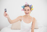 Excited natural brown haired woman in hair curlers holding a credit card