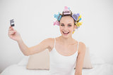 Content natural brown haired woman in hair curlers holding a credit card
